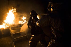 Firefighter spraying a hose inside a fire training bay